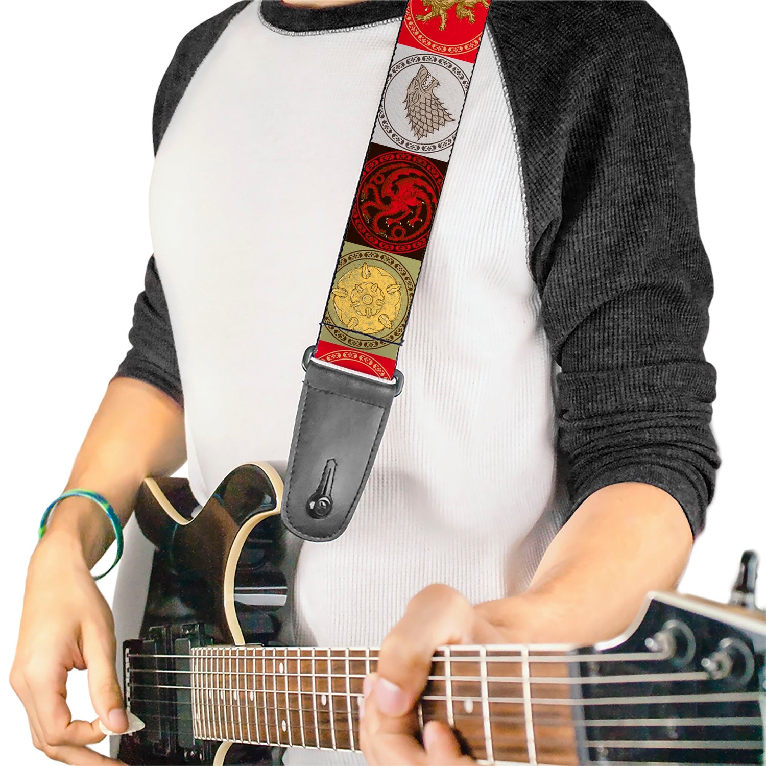 Person playing electric guitar, wearing a white and black shirt, with a strap featuring Game of Thrones house sigils.