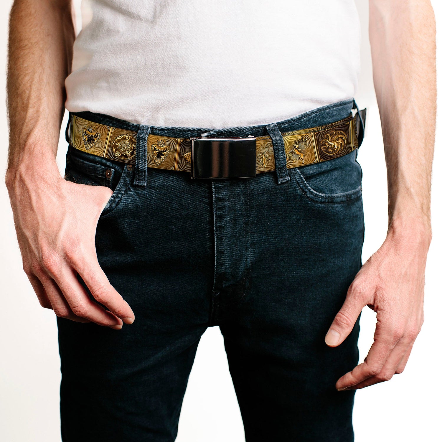 A person wears a white shirt, dark jeans, and an ornate gold belt with various house sigils. One hand is in a pocket.